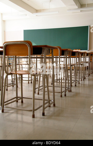 Empty classroom due to shutdown. Only school desks, chairs and a blackboard. No students. Stock Photo
