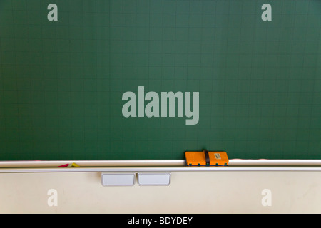 A blackboard with an eraser and white, red and yellow chalk. Stock Photo