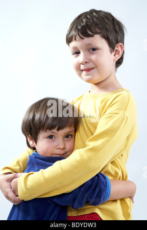 Six-year-old boy hugging his three-year-old sister Stock Photo