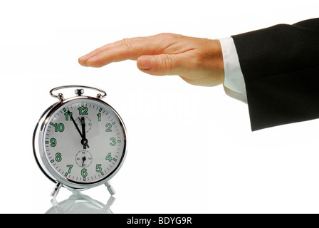 Business man's hand with an alarm clock set at 5 to 12, just before high noon, symbolic image for action in a crisis Stock Photo