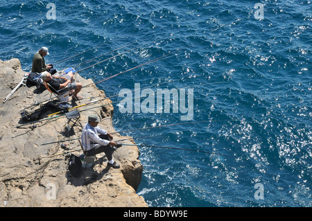 Three fishermen on a rocky coast, Cascais near Lisbon, Portugal, Europe Stock Photo