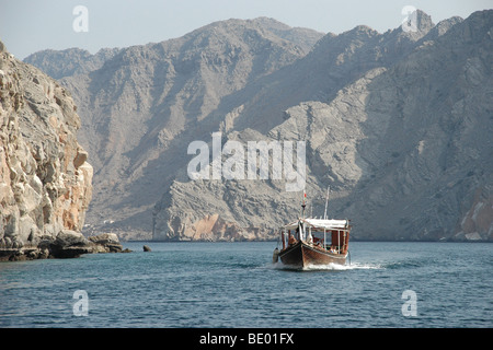 A dhow boat moving through the fjords of the Musandam Peninsula near Telegraph Island, just below the Strait of Hormuz, in the Sultanate of Oman. Stock Photo