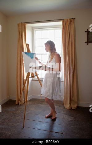 Young woman painting by window Stock Photo