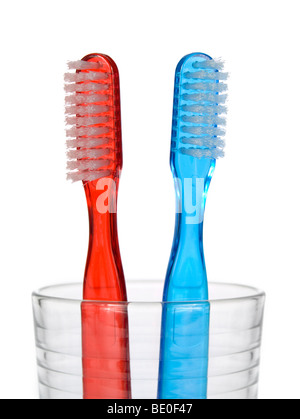 Two toothbrushes in a glass over white background. Stock Photo