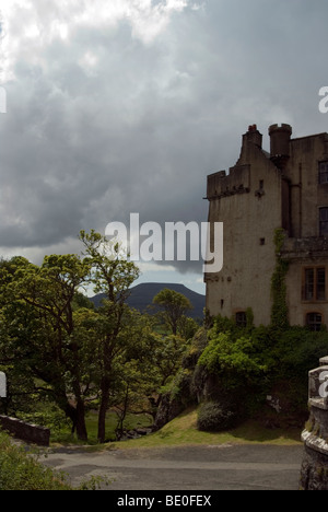 Portrait view of dunvegan castle to the right of the image with a stormy grey sky and the macleod table mountain to the left Stock Photo