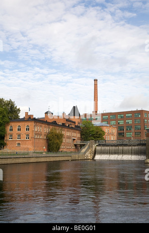 Red brick buildings - former industrial buildings - in the city of Tampere, Finland. The Tammerkoski Rapids can also be seen. Stock Photo