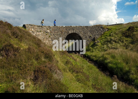 Old drystone bridge with one arch in the hills of the Isle of Skye called the fairy bridge with menacing cloud behind it Stock Photo