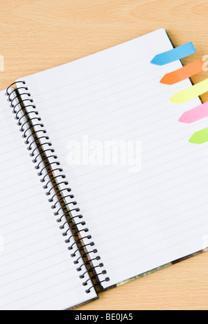 Lined spiral notepad with colorful postit sticky notes isolated on wooden background Stock Photo