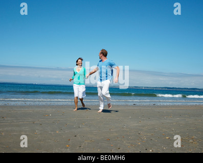 A couple running hand in hand on the beach Stock Photo