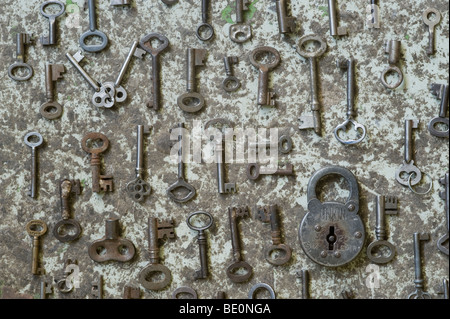 Group of ornate and antique keys with a single aged padlock arranged in lines against concrete background. Stock Photo