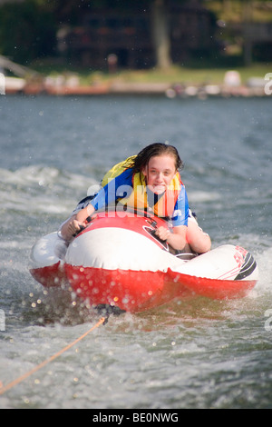 Teenager water surfing on a lake using a water craft - skibob - and being pulled by a motorboat. Stock Photo