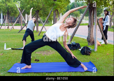 People Stretching Doing Yoga Outdoors In Park Stock Photo