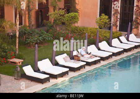 Single businessman sat by the side of a hotel pool working Stock Photo