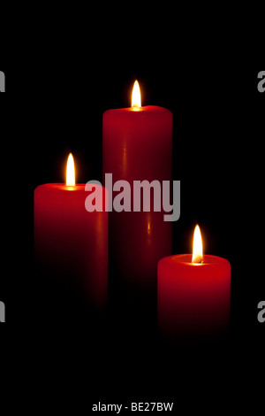 Three red burning candles against black Stock Photo