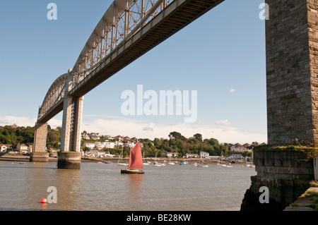 On the Devon and Cornwall border a sailing boat passes under The Royal Albert Bridge on the River Tamar. Stock Photo