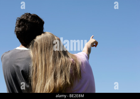 Romantic teenage couple looking at blue sky. Girlfriend pointing Stock Photo