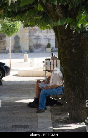 2 french people sitting under a tree relaxing from the sun in thiviers france Stock Photo