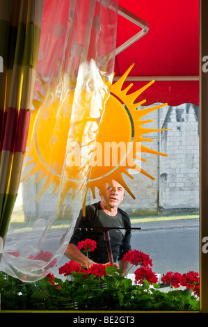 Man cleaning restaurant window with squeegee - France. Stock Photo