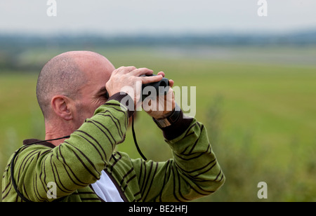 Man looking through a pair of binoculars Stock Photo