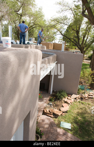two plumbers install a heating and cooling unit on a roof, Albuquerque New Mexico, USA Stock Photo