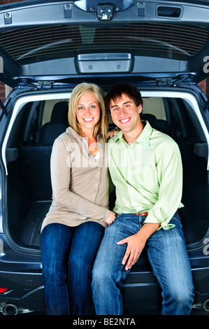Happy young couple sitting at back of car Stock Photo