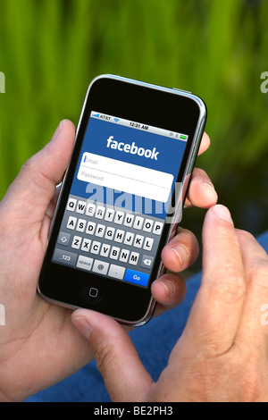 Woman hand holding an iPhone showing Facebook screen Stock Photo