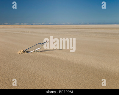 A bottle with a message inside is abandoned in the desert. Stock Photo