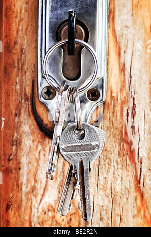 Set of keys in lock of old wooden door Stock Photo