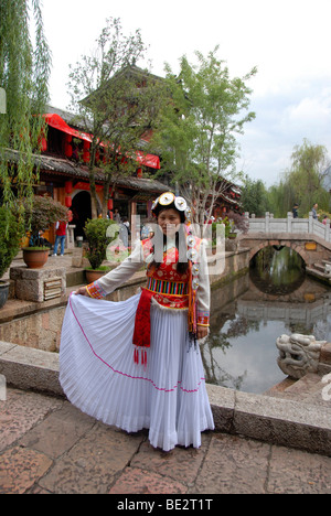 Young women in a colorful dress on a bridge in front of the old market square, historic centre, Lijiang, UNESCO World Heritage  Stock Photo