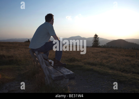 Man, mid 40s, sitting on a bench and looking into the distance, Black Forest, Baden-Wuerttemberg, Germany, Europe Stock Photo