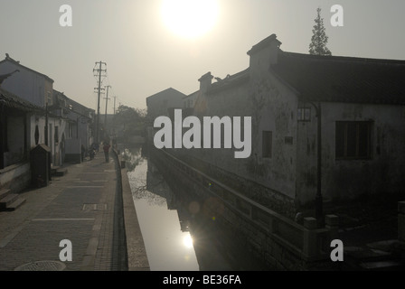 Backlit mood with ancient Chinese buildings in a quiet alleyway with a canal in the historic town centre of Suzhou, China, Asia Stock Photo