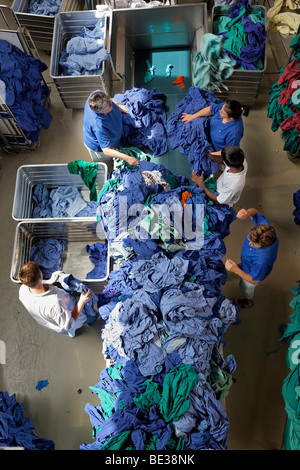 Green and blue hospital clothes being sorted by type and colour after being washed in an industrial laundry, Textil-Mietdienst  Stock Photo