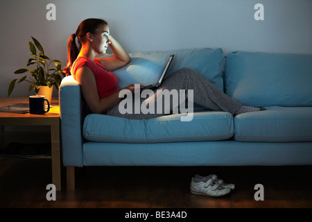 Young woman on sofa with laptop Stock Photo