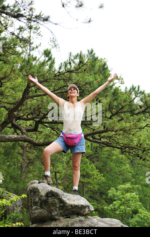 Woman hiker standing on a rock with her arms wide open Stock Photo