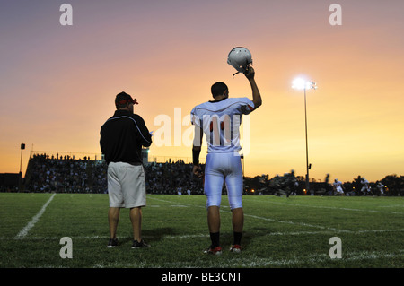 Football game at a high school with player and coach watching Stock Photo