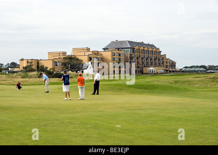 Golfers holing out on the 17th green of the Old Course in St Andrews Scotland with the Old Course Hotel in the backtround