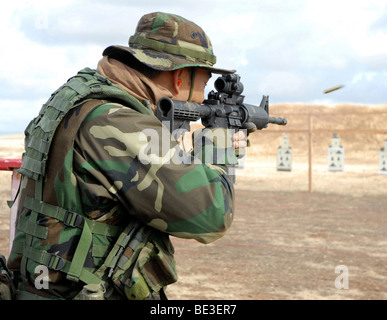 A soldier fires rounds down range at an M-4 qualification shoot. Stock Photo
