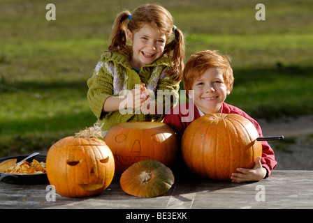 Two children carving pumpkins for Halloween decoration Stock Photo