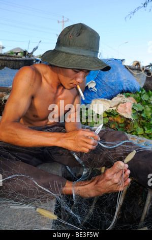 Young fisherman repairing his net, Mui Ne, Vietnam, Asia Stock Photo