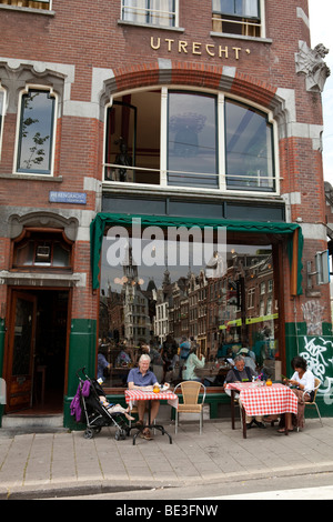 Restaurant with tables outdoor in the street and reflection of the traditional houses in the window. Amsterdam, Holland Stock Photo
