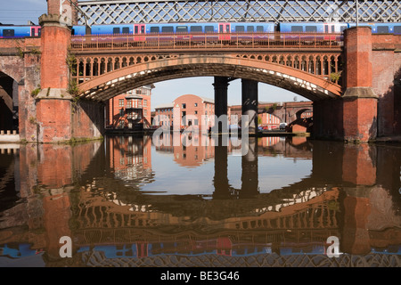 Train crossing Victorian railway viaduct bridge over Bridgewater Canal in Castlefield Urban Heritage Park conservation area. Manchester, England, UK. Stock Photo