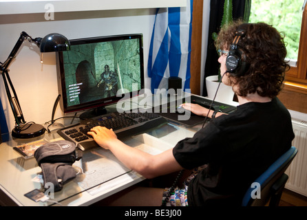 A boy, about 15, playing a violent game on the computer in his room, Germany, Europe Stock Photo