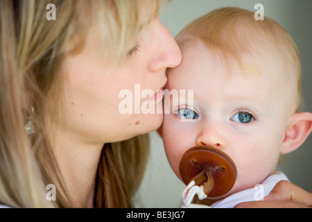 A one-year-old girl on the arm of her mother Stock Photo