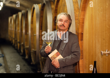 The winegrower Reinhard Heymann-Loewenstein with his book 'Terroir' in his wine cellar in Winningen, Rhineland-Palatinate, Germ Stock Photo