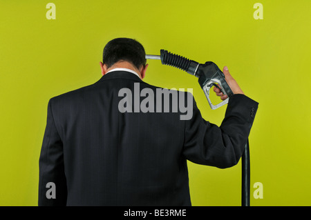 Businessman committing suicide with a gas nuzzle isolated on a green background Stock Photo