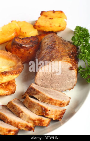 A beef 'eye roast' joint, sliced into medallions, on a plate with roast potatoes and Yorkshire puddings. Stock Photo