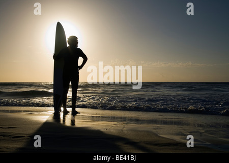 Man standing with surfboard at sunrise.  Bondi Beach. Sydney, New South Wales, AUSTRALIA Stock Photo