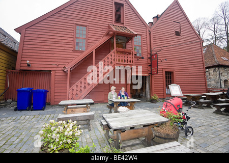 Young mothers sit with babies in front of wood houses near the harbor area of Bergen, Norway. Stock Photo