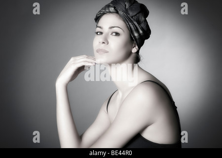 Young dark-haired woman with a headscarf holding her hand to her chin, looking at the viewer, side portrait Stock Photo