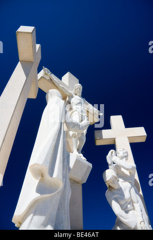 White marble statues of Jesus Christ on the cross, surrounded by the Virgin Mary and two empty crosses in Fatima, Portugal. Stock Photo